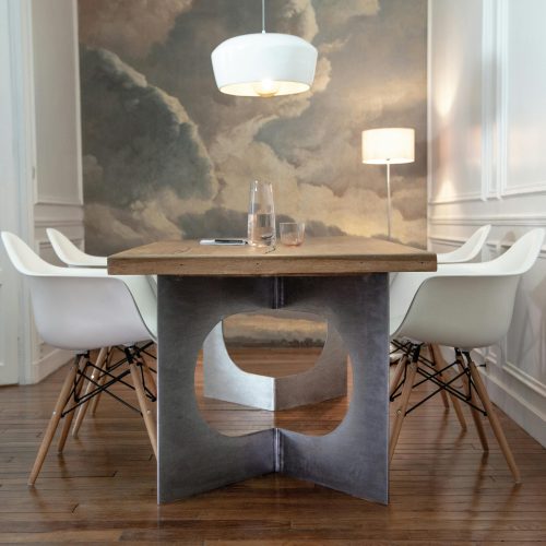 Modern dining room featuring sleek furniture, wooden table, and artistic wall painting.
